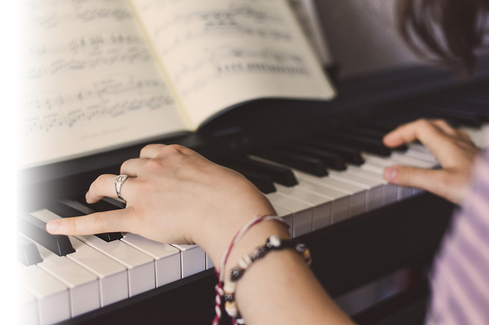 Woman learning to play piano with a private music teacher